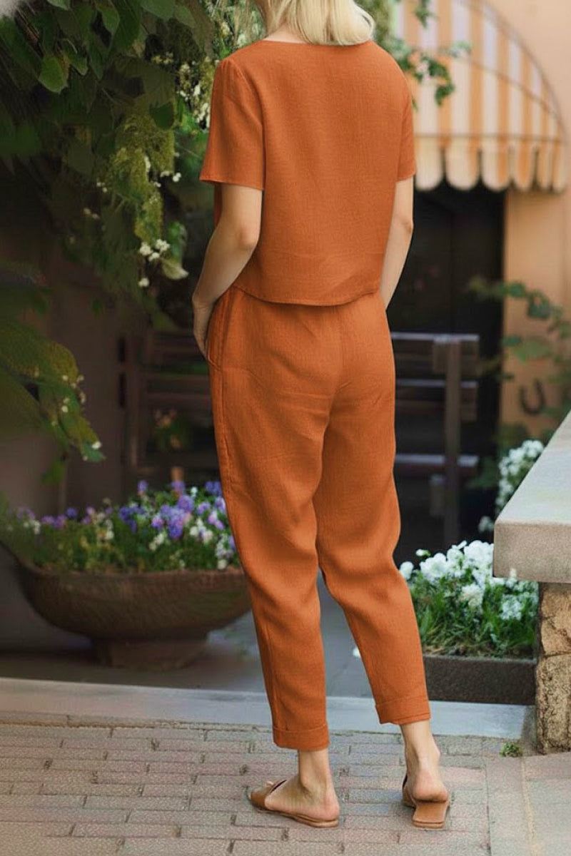 Woman wearing orange cotton linen set with short-sleeve top and straight-leg pants outdoors