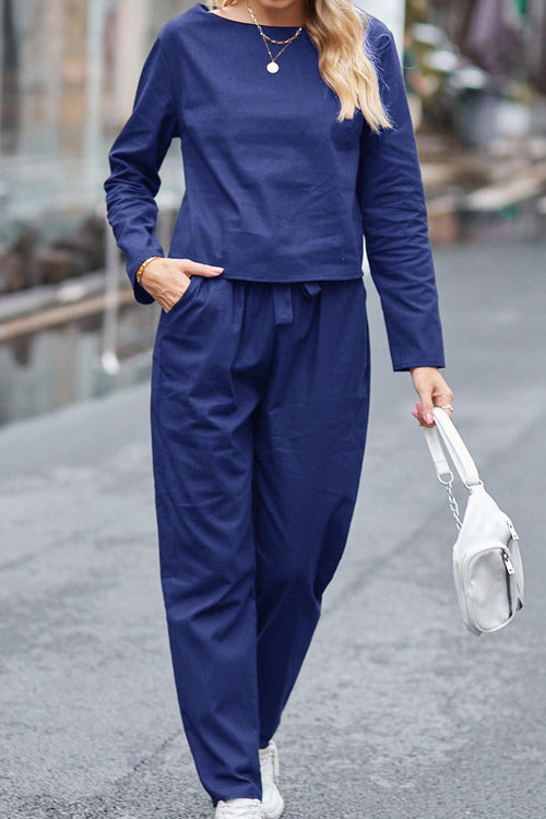 Woman wearing navy blue 100% cotton linen monochrome two-piece set carrying white handbag outdoors