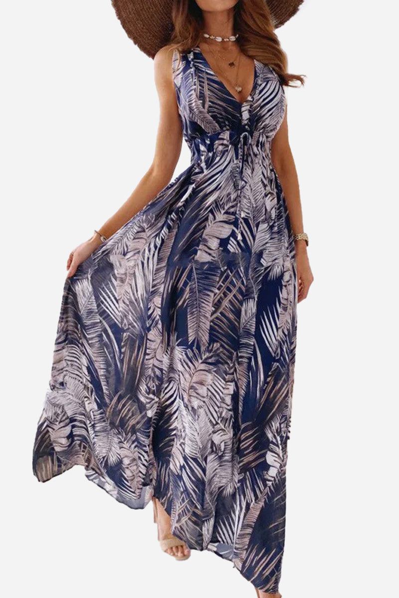 Woman wearing a navy blue and white casual sleeveless print strap dress with tropical leaf pattern and wide-brim hat
