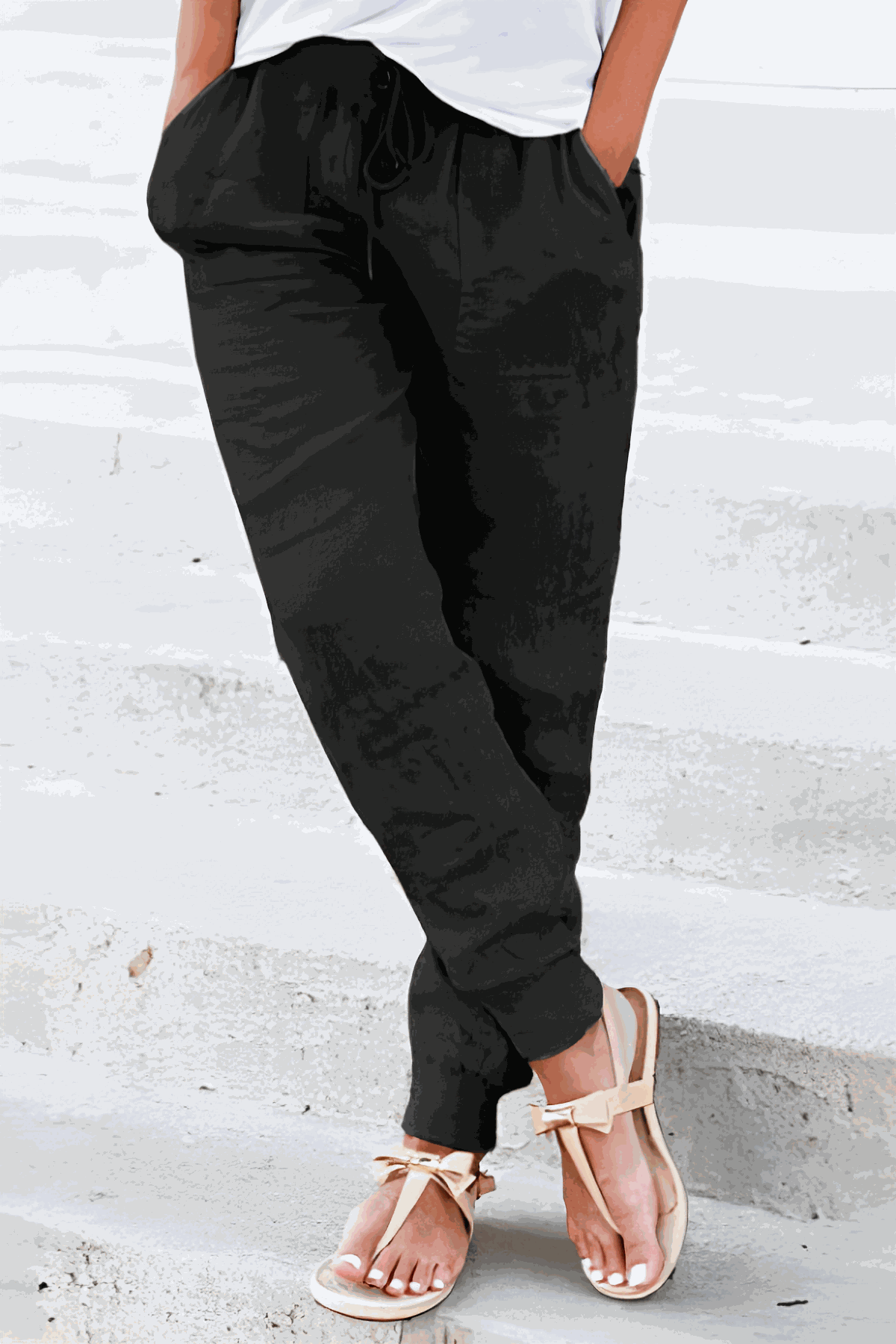 Woman wearing relaxed chic elastic ankles pants standing outdoors on a street with palm trees in the background