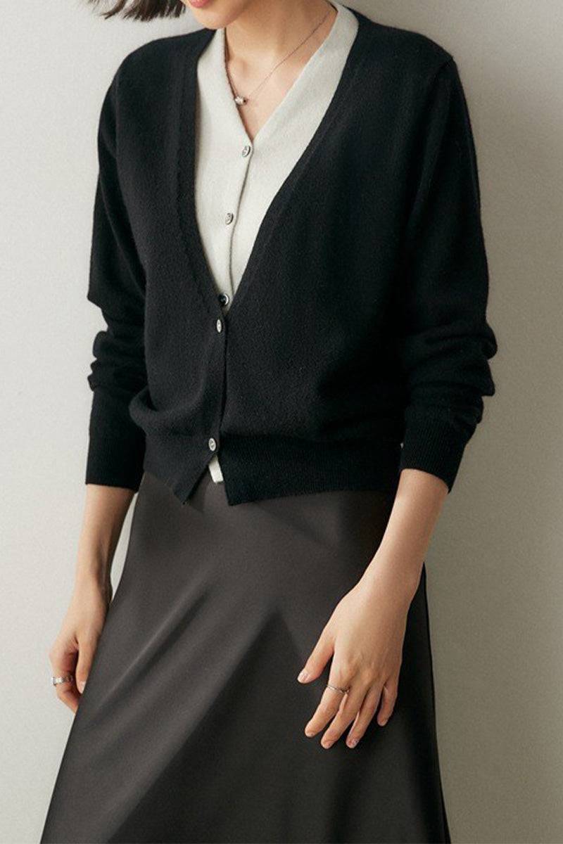 Woman wearing a black single-breasted cashmere wool cardigan over a light blouse and dark skirt