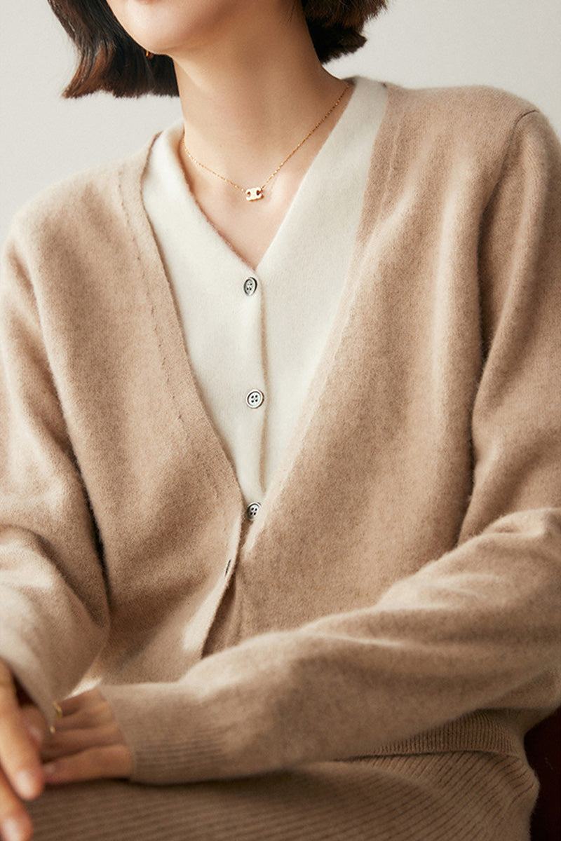 Woman wearing a beige single-breasted cashmere wool cardigan with white inner shirt and gold necklace