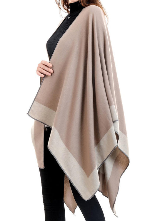 Elegant knitted poncho in two-tone beige draped over woman wearing black outfit