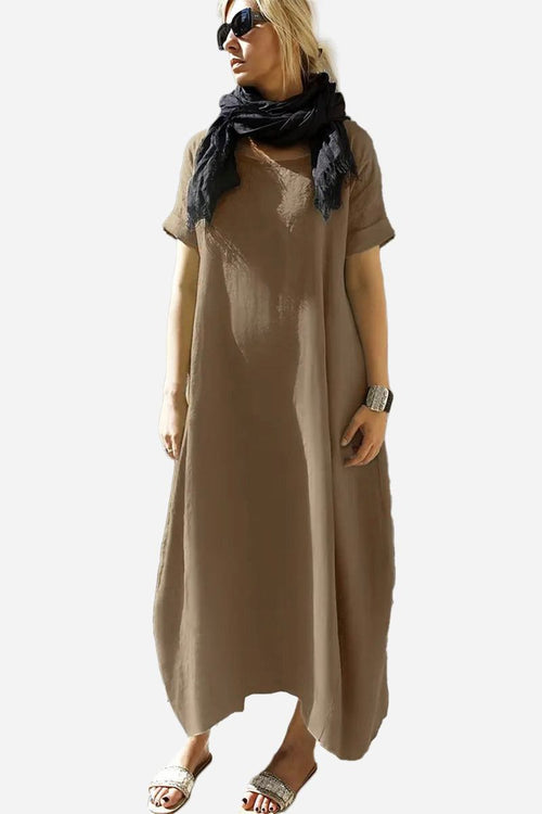 Woman wearing a relaxed brown Breeze Cocoon Dress with rolled sleeves, deep side pockets, and a black scarf.