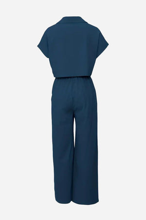 Back view of navy blue two piece set with big pockets, featuring a cropped top and wide-leg pants, made from wrinkle-resistant fabric.