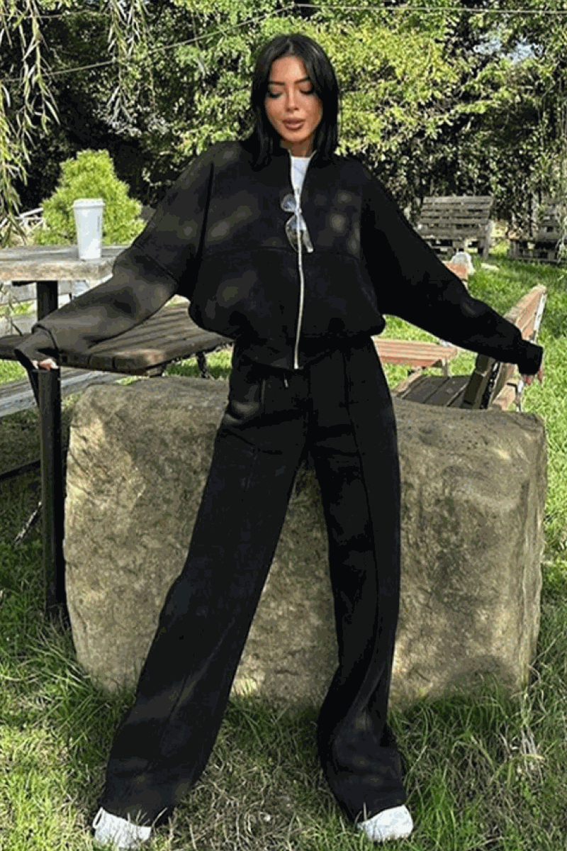 Woman wearing The Voyager Zip Set black zip-front sweatshirt and wide-leg joggers outdoors