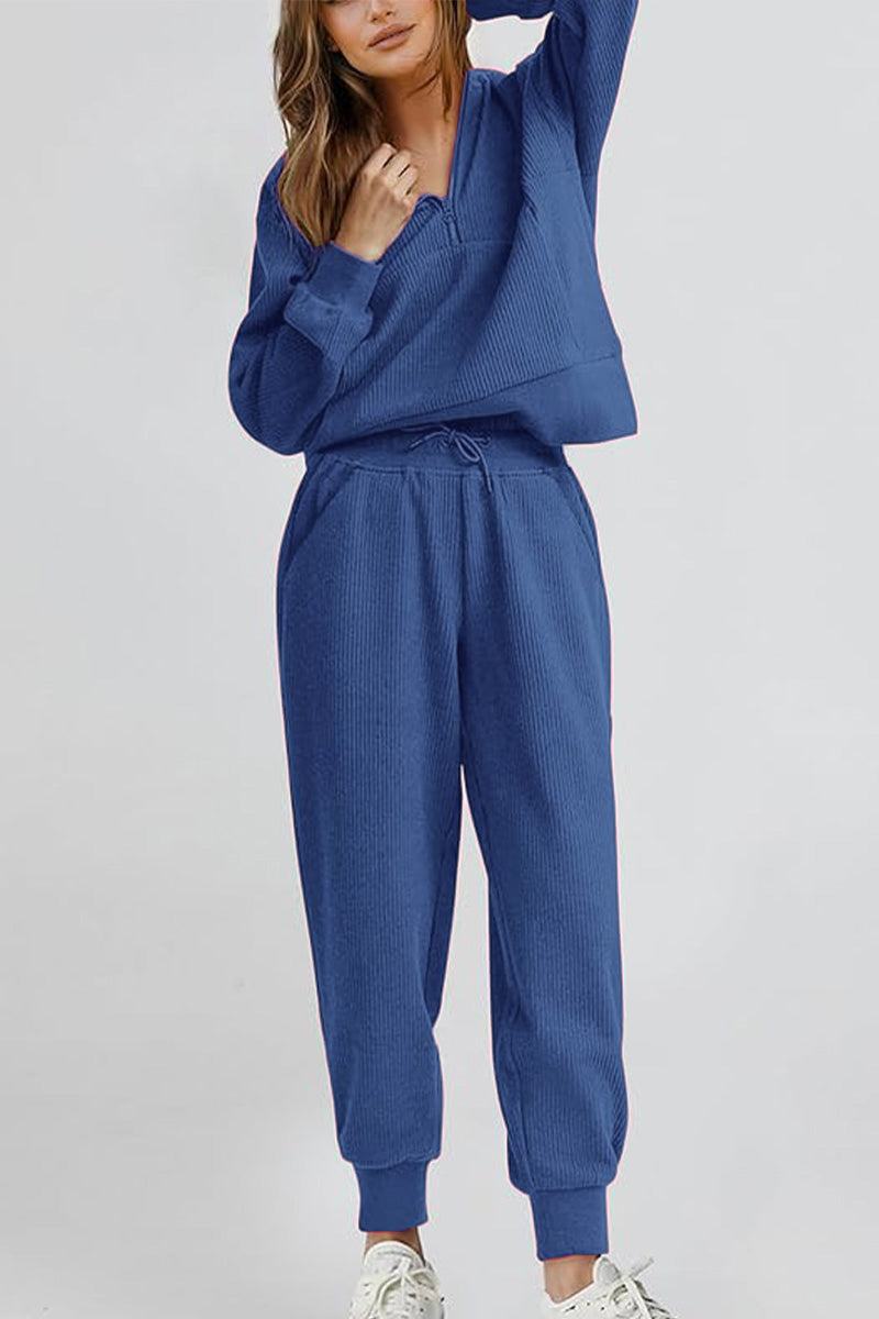 Woman wearing blue unisex half-zip pullover and sweatpants set, casual comfortable fit.