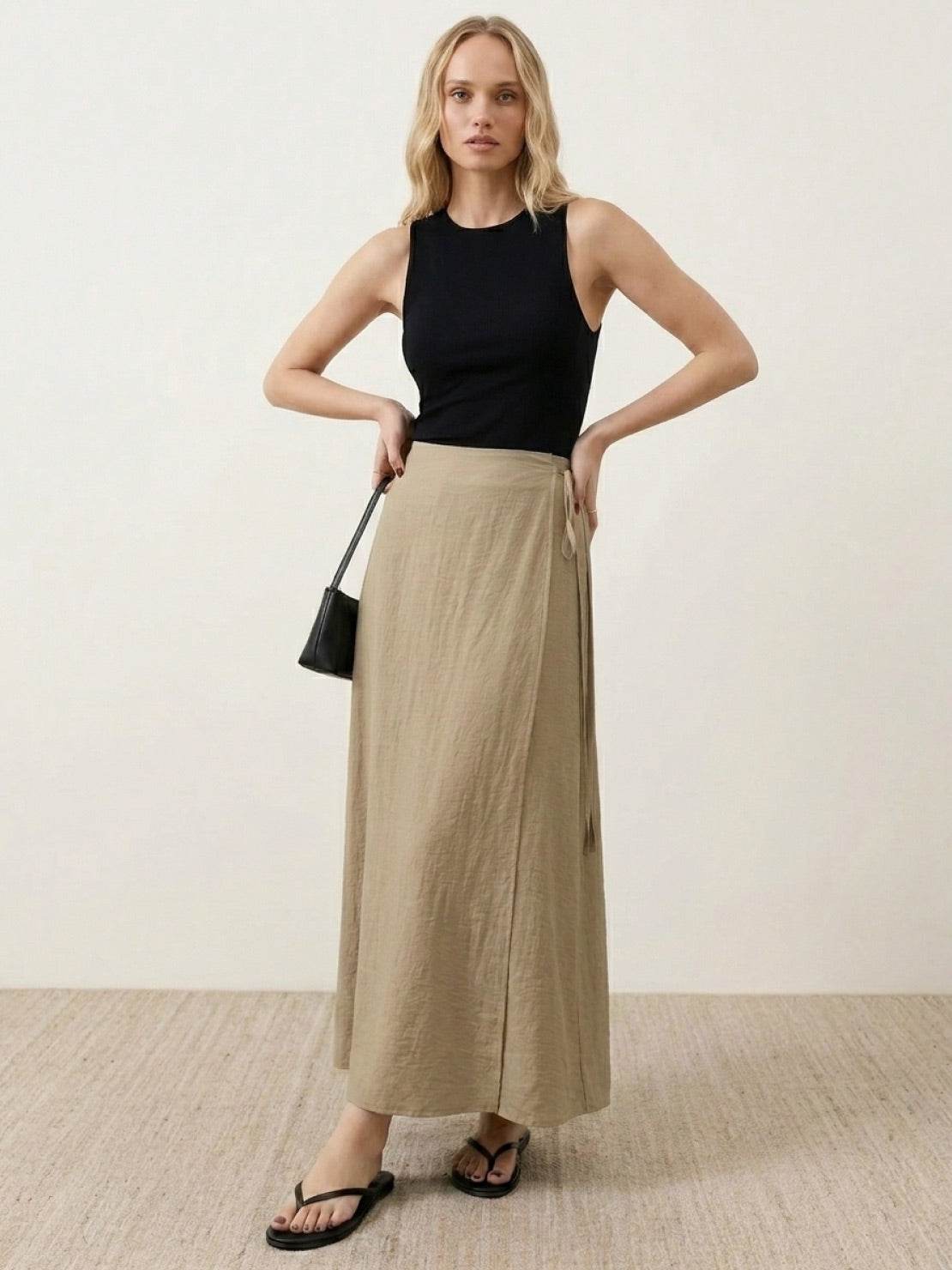 Woman wearing asymmetrical wrap maxi skirt with side tie and flowing asymmetric hem.
