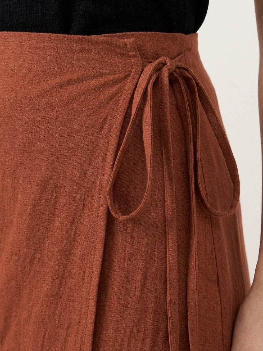 Woman wearing asymmetrical wrap maxi skirt with side tie closure and flowing asymmetric hem in a casual outdoor setting