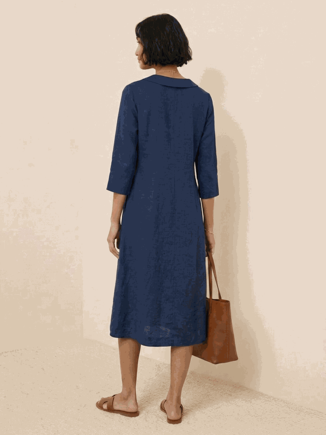 Woman wearing a navy linen-look midi dress with 3/4 sleeves and side pockets standing outdoors
