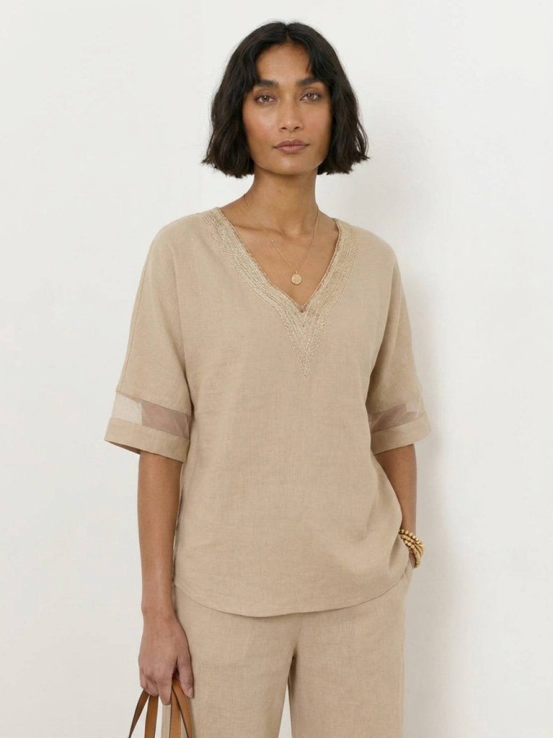 Mature woman wearing lightweight linen top with V-neck and button detail in light khaki