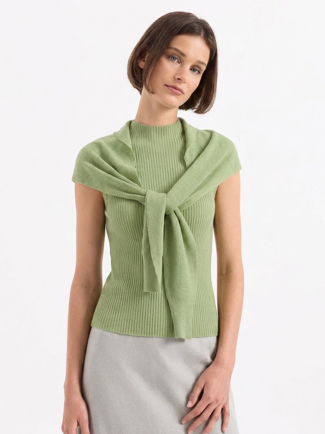 Beige knit vest with attached scarf in fine ribbed knit, sleeveless with mock neckline, styled over white blouse and black pants
