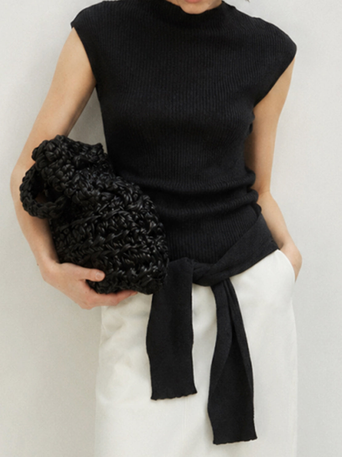 Beige knit vest with attached scarf, sleeveless ribbed design, and mock neckline for versatile styling.