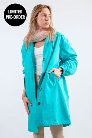 Woman wearing oversized turquoise water-resistant windbreaker rain jacket with hood and buttons
