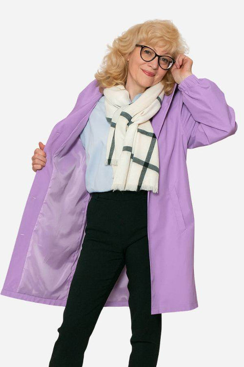 Woman wearing a lavender water-resistant oversized windbreaker opening the jacket showing interior lining.