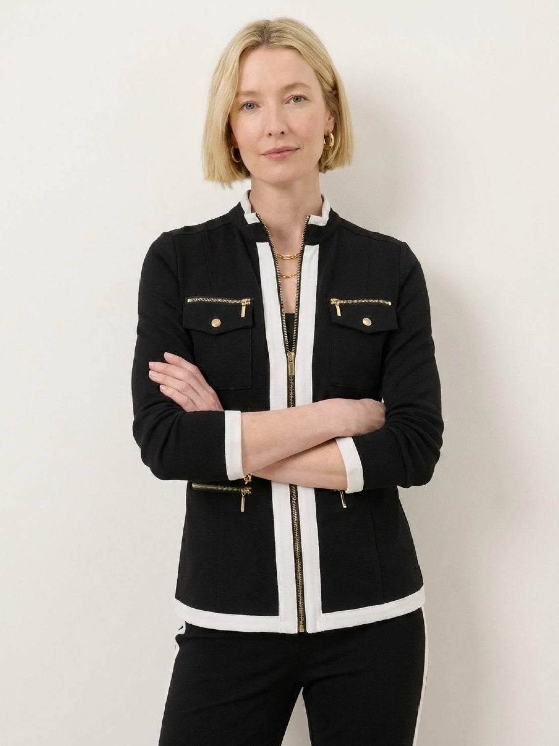 Woman wearing sleek black contrast zip two-piece outfit against white background