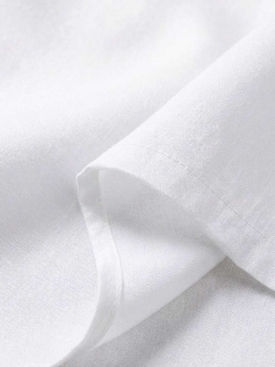 Close-up of white breathable fabric texture from asymmetrical two-piece trouser set