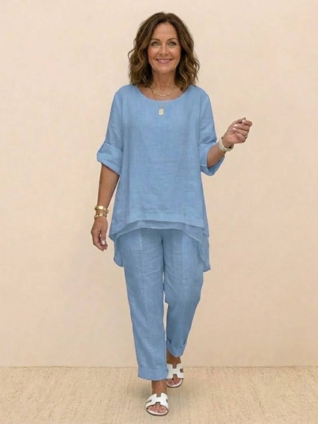 Woman wearing light blue asymmetrical two-piece trouser set with rolled-up sleeves and tapered pants