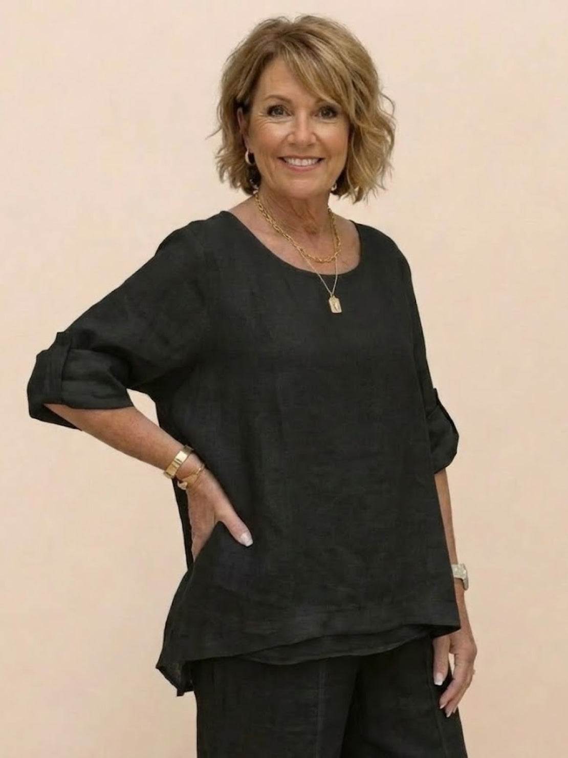 Woman wearing black asymmetrical two-piece trouser set with rolled-up sleeves and loose fit