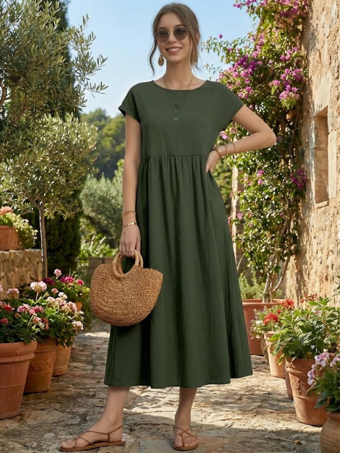 Woman wearing capped-sleeve voluminous pleated midi dress with flowing skirt and pockets