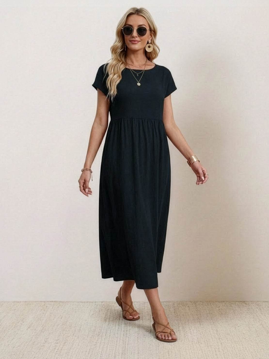 Woman wearing capped-sleeve voluminous pleated midi dress with flowing skirt and pockets