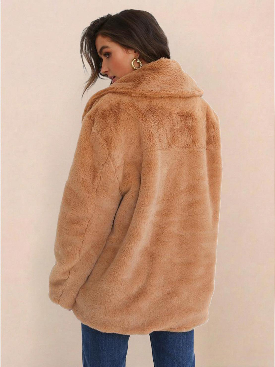 Woman wearing tan open front oversized faux fur jacket with draped collar and mid-hip length shown from back