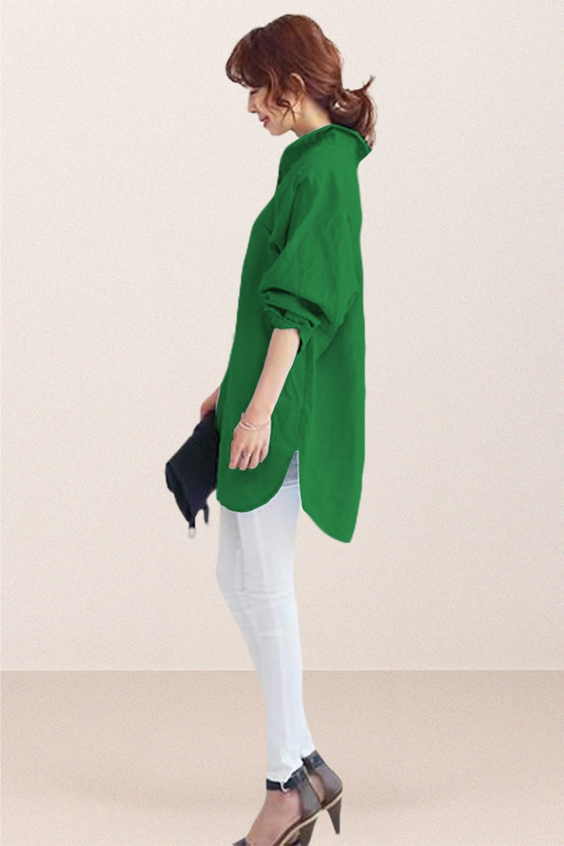 Woman wearing oversized green linen shirt with rolled sleeves and white pants, holding a black clutch.