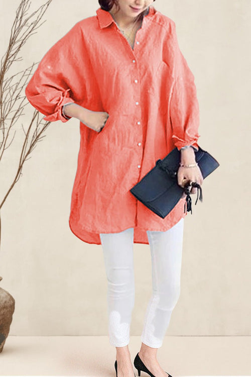 Woman wearing oversized linen shirt in sun-washed pink with white pants and black clutch handbag