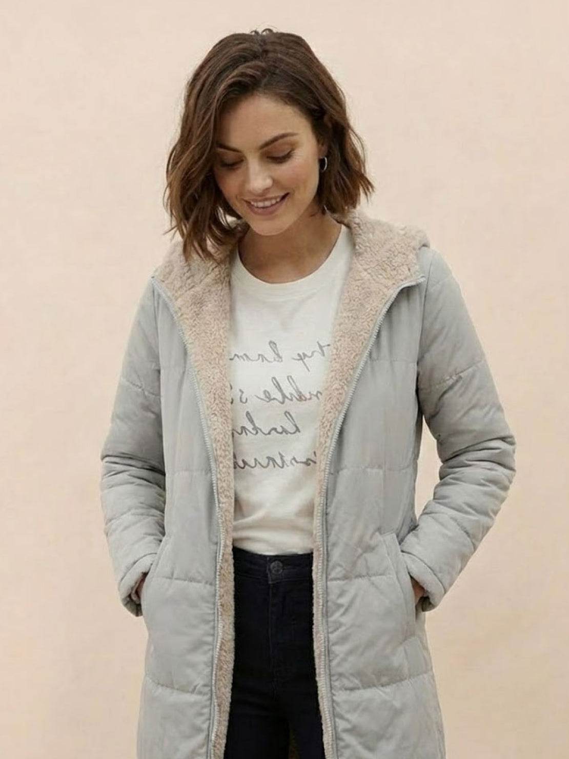 Woman wearing a light gray Sherpa-lined hooded teddy coat with soft inner lining and front pockets