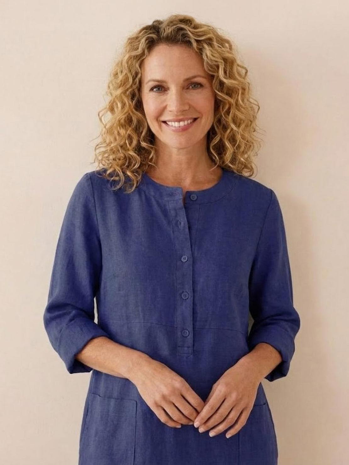 Woman wearing a timeless class cotton dress in blue with ¾ rolled sleeves and button front detail