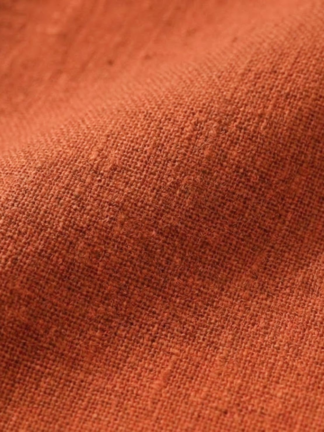 Close-up of soft lightweight cotton fabric texture in warm earthy orange for cotton dress