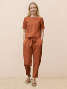 Woman wearing relaxed cotton linen set with monochrome top and straight-leg pants standing against white background