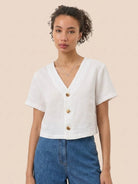 Lightweight 100% linen French top with V-neck, short sleeves, three-button front, relaxed boxy fit, and cropped hem in light khaki and off white colors