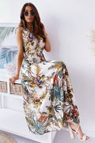Woman wearing a colorful floral casual sleeveless dress with sunglasses and heels sitting indoors