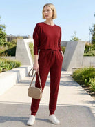 Woman wearing Cozy Chic Two-Piece Sweatsuit set with long-sleeve top and high-waisted pants with pockets