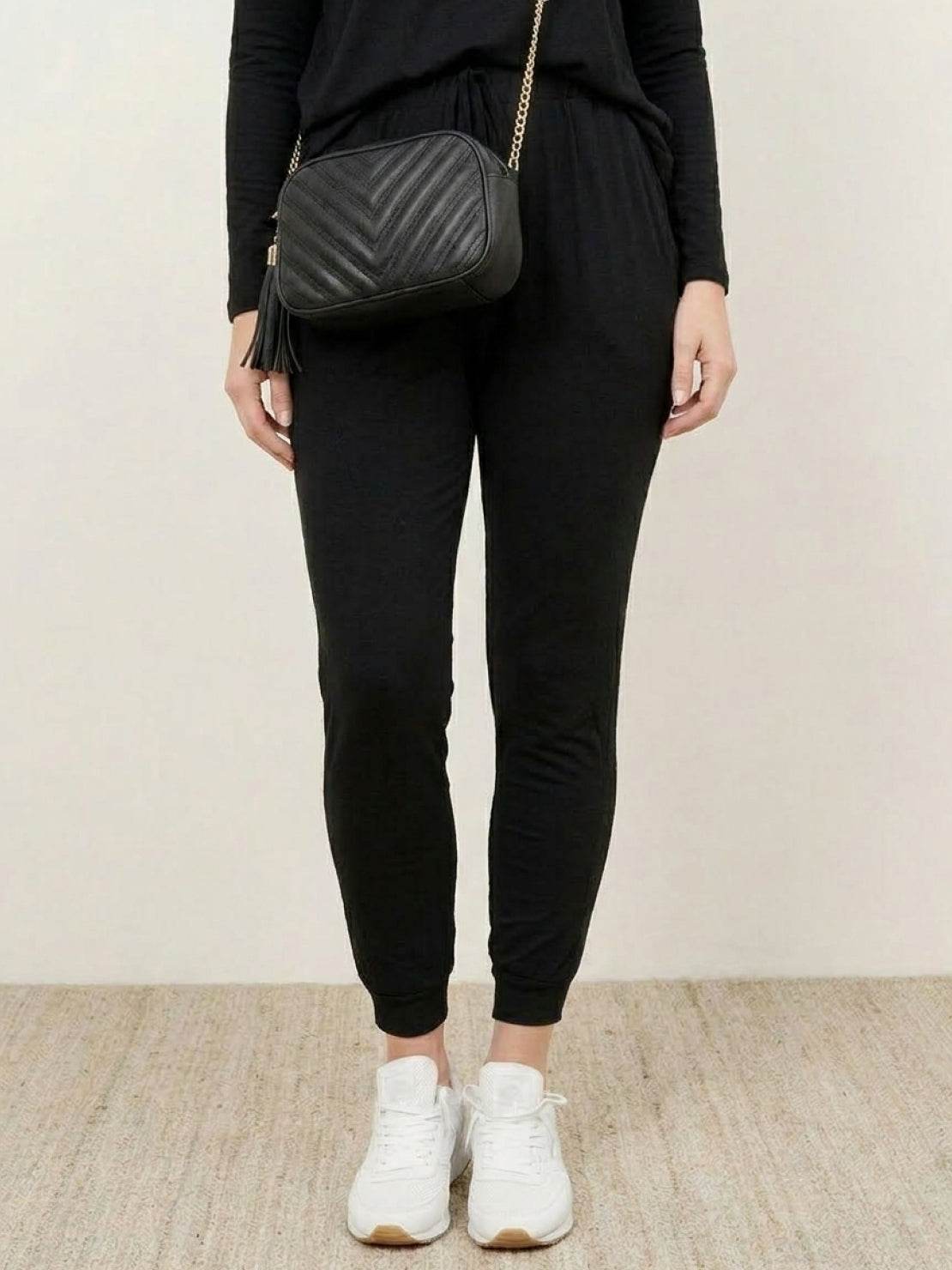 Woman wearing Cozy Chic Two-Piece Sweatsuit set with long-sleeve top and high-waisted pants, styled for comfort and travel.