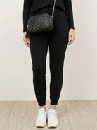 Woman wearing Cozy Chic Two-Piece Sweatsuit set with long-sleeve top and high-waisted pants, styled for comfort and travel.