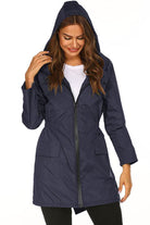 Woman wearing navy blue outdoor and travel hooded raincoat windbreaker jacket with front zipper and pockets
