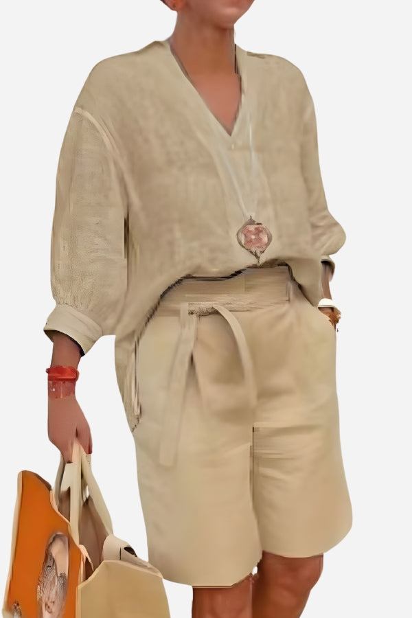 Beige two-piece set with loose V-neck shirt and high-waisted knee-length shorts with pockets, made of breathable cotton fabric.