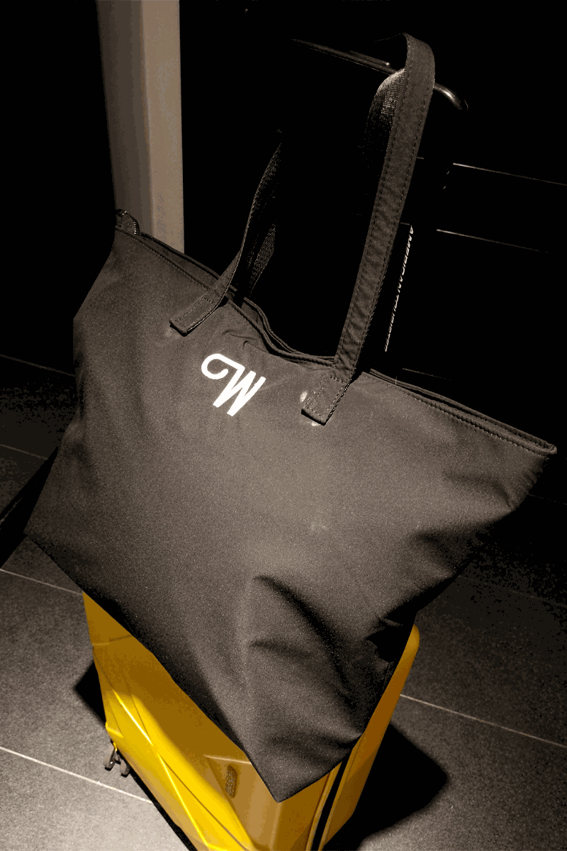 black waterproof travel bag with sturdy handles on yellow suitcase in dim light