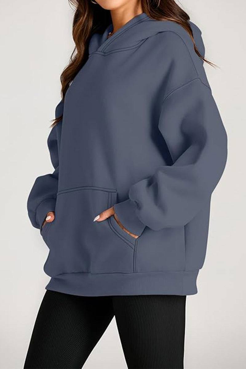 Woman wearing oversized fleece-lined hoodie in slate blue with front pocket and relaxed fit