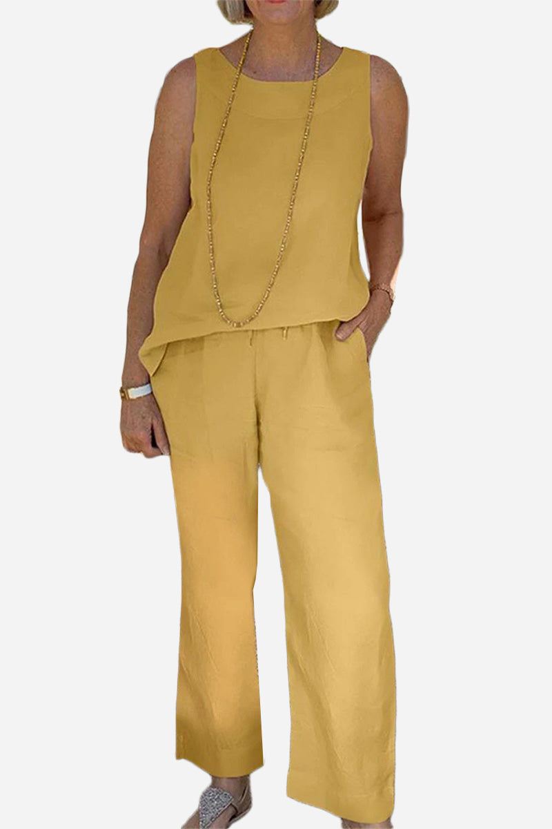 Woman wearing mustard yellow sleeveless sleek silhouette coordinated set with wide-leg pants and layered necklace