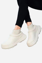 White fleece-lined comfort clogs with waterproof exterior and textured sole worn with black leggings