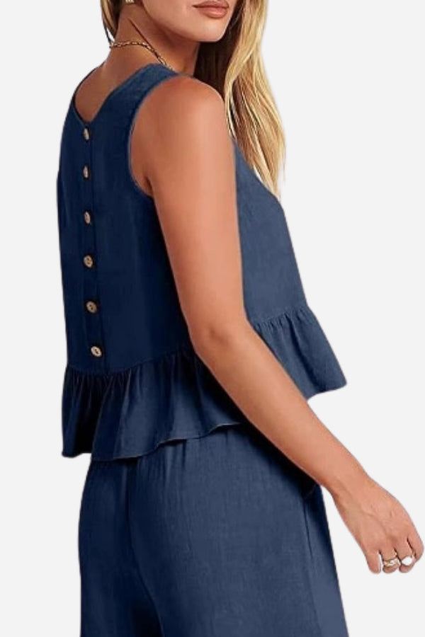 Woman wearing navy linen-like feel sleeveless top and pants set with buttoned back and peplum hem detail