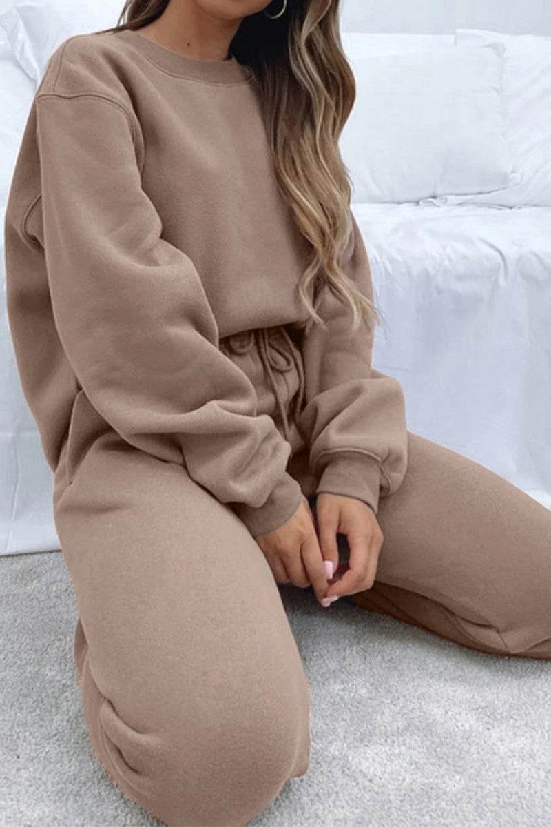 woman wearing brown Classic Comfort Athleisure set sitting on carpet with white background