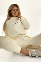 Woman wearing cream Storm Sweater Mock Neck athleisure set with relaxed fit and sporty sneakers