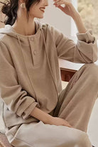 Woman wearing beige Quiet Comfort Everyday two-piece ribbed knit set with henley hoodie and wide-leg pants lounging indoors