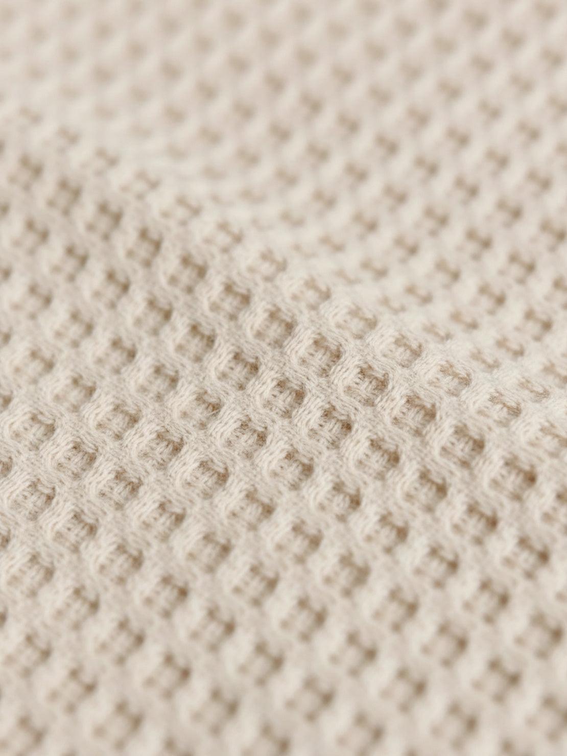 Close-up of soft breathable beige cotton waffle knit fabric texture