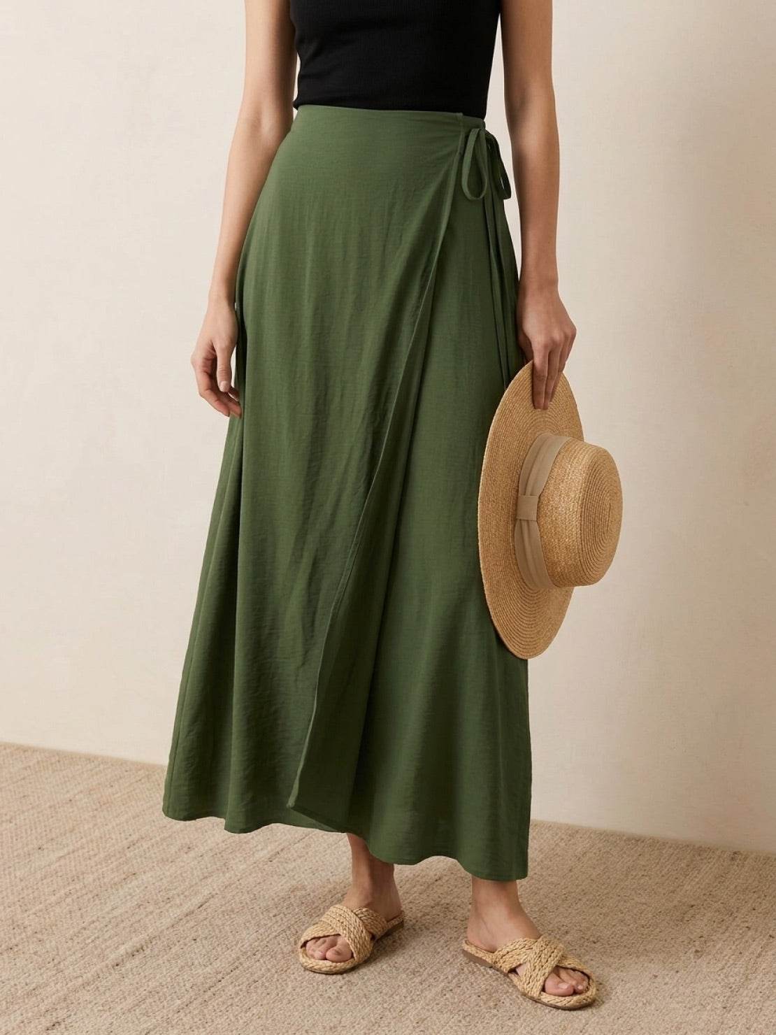 Woman wearing an army green asymmetrical wrap maxi skirt with side tie closure and flowing fabric