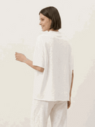Woman wearing a chocolate brown cotton-blend capelet lounge set with batwing sleeves and wide-leg pants